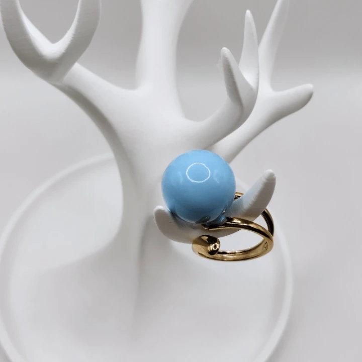 Regulowany pierścionek z dużą błękitną kulą i złotą obrączką to elegancki dodatek o nowoczesnym charakterze. Minimalistyczny design doskonale uzupełnia codzienne i wizytowe stylizacje.